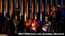 Una niña migrante sostiene un regalo de Navidad mientras hace cola con su familia cerca del muro fronterizo en El Paso, Texas, el 25 de diciembre de 2022.