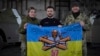 El presidente ucraniano Volodymyr Zelenskyy, en el centro, y los soldados ucranianos sostienen la bandera de una unidad militar en una posición cerca de Bakhmut, región de Donetsk, Ucrania.