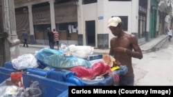 Un joven busca alimentos en la basura, en una esquina de La Habana.