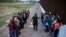 Un grupo de migrantes espera a ser procesado junto al muro fronterizo, en Eagle Pass, Texas. (AP/Dario Lopez-Mills, File)