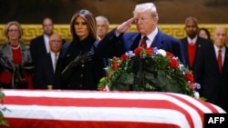 El presidente Donald Trump y la primera dama Melania Trump presentan sus respetos frente al féretro del expresidente George H. W. Bush.