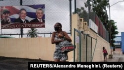 Mujer pasa frente a cartel de propaganda de continuidad. REUTERS/Alexandre Meneghini.