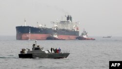 Una lancha militar iraní patrulla las aguas mientras un petrolero se prepara para atracar en las instalaciones petroleras en la isla de Khark, en Irán.