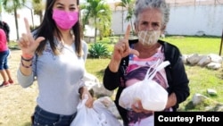 Roxana García Lorenzo, una de las promotoras de la iniciativa, entrega la ayuda a la familiar de tres de los detenidos.