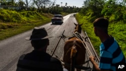Autos, camiones, peatones y carretones de caballo confluyen en las carreteras cubanas.