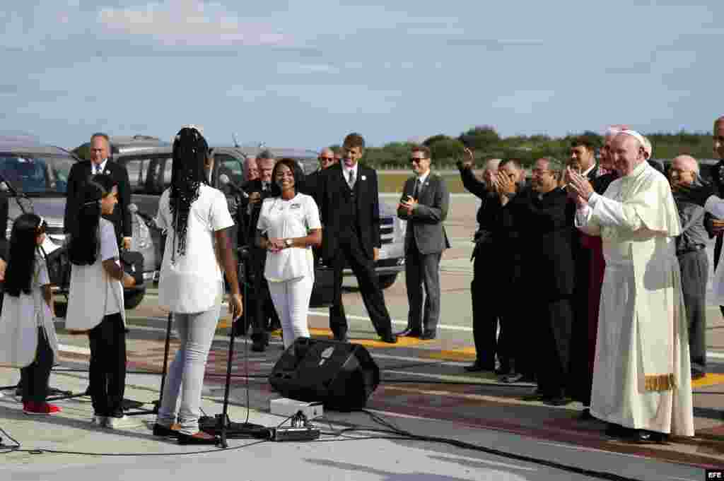 El papa Francisco es recibido por un coro de niños a su llegada al aeropuerto de Santiago de Cuba.