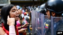 Una manifestante increpa a la policía antimotines durante una protesta contra Nicolás Maduro en Caracas.