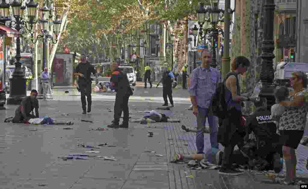Varias víctimas en el suelo en el lugar del atropello masivo realizado por una furgoneta que ha arrollado esta tarde a varios viandantes que paseaban por las Ramblas de Barcelona. Los Mossos d'Esquadra y los equipos de emergencias sanitarias han desplega