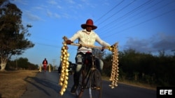 Dos vendedores ambulantes de ajos y cebollas transitan por una carretera rural de Pinar del Río (Cuba).