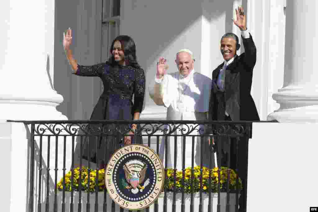 El papa Francisco, el presidente Barack Obama y la primera dama Michelle Obama saludan desde un balcón de la Casa Blanca.