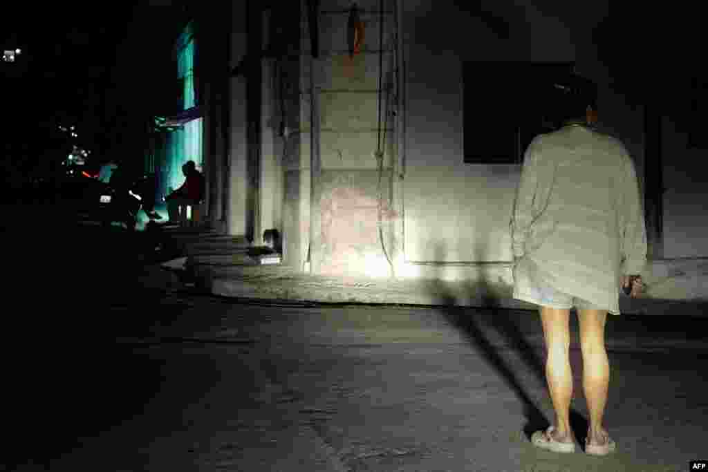Una mujer está parada en una calle iluminada por las luces de un automóvil durante un apagón nacional  el 4 de diciembre de 2024.