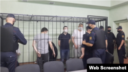 Ihar Losik (camiseta oscura) y Syarhey Tsikhanousky (camiseta blanca) tras ser conducidos a la jaula de los acusados en la apertura de su juicio a puerta cerrada en un centro de detención en Homel, Bielorrusia, el 24 de junio de 2021.