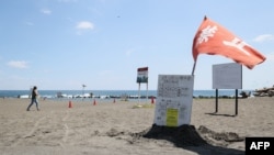 Una bandera roja ondea al viento mientras las autoridades advierten no nadar en una playa en Hiratsuka, al suroeste de Tokio, tras el "aviso de megasismo" del gobierno. (Foto: JIJI PRESS / AFP)