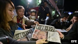 Una empleada de un periódico ofrece a unos viandantes ejemplares de una edición extraordinaria, en la que se informa sobre la victoria del candidato republicano a la presidencia estadounidense, Donald Trump, en Tokio (Japón) hoy, 9 de noviembre de 2016.