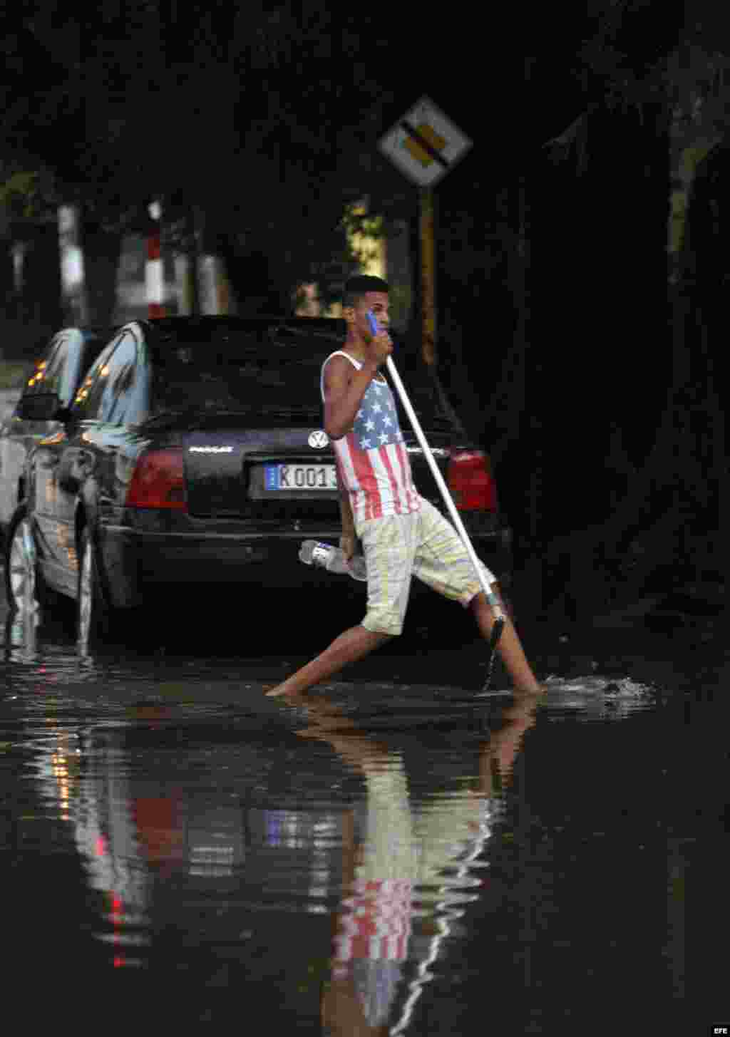 Un joven cruza una calle inundada hoy, miércoles 29 de abril de 2015, en La Habana (Cuba).