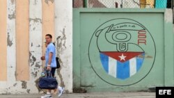 Una pareja camina junto a un cartel con el emblema de los Comités de Defensa de la Revolución (CDR), en La Habana, Cuba.