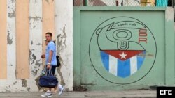 Una pareja camina junto a un cartel con el emblema de los Comités de Defensa de la Revolución (CDR), en La Habana, Cuba.