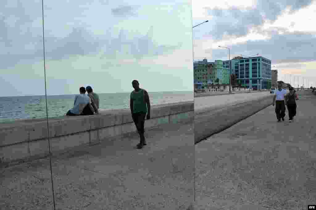 Dos hombres caminan junto a la obra ""Happily Ever After", de la artista cubana Rachel Valdés Camejo, colocada en el malecón de La Habana (Cuba) como parte de la XI Bienal de La Habana.