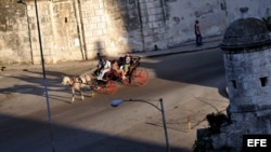 Turistas pasean en un coche de caballos por una avenida de la Habana Vieja.