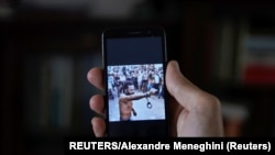 Un hombre que no quiso ser identificado muestra en su teléfono al rapero contestatario Maykel Castillo El Osorbo. (REUTERS/Alexandre Meneghini)