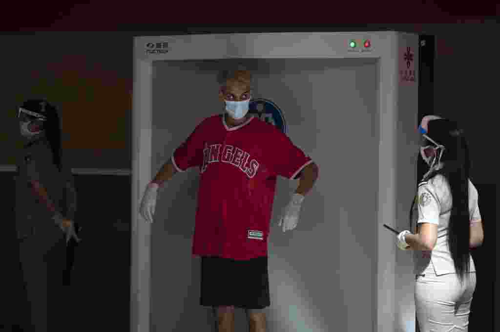 Con mascarilla como medida de prevención ante el nuevo coronavirus, un hombre sigue las instrucciones durante una revisión de seguridad en el Aeropuerto Internacional José Martí de La Habana. (AP Foto/Ramon Espinosa)