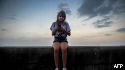 Una joven intenta conectarse a Internet en el Malecón habanero.