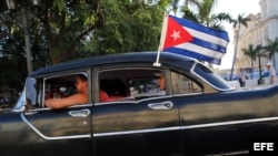 Un viejo taxi con una bandera cubana.
