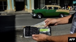 Un hombre muestra su cartera con dólares estadounidenses