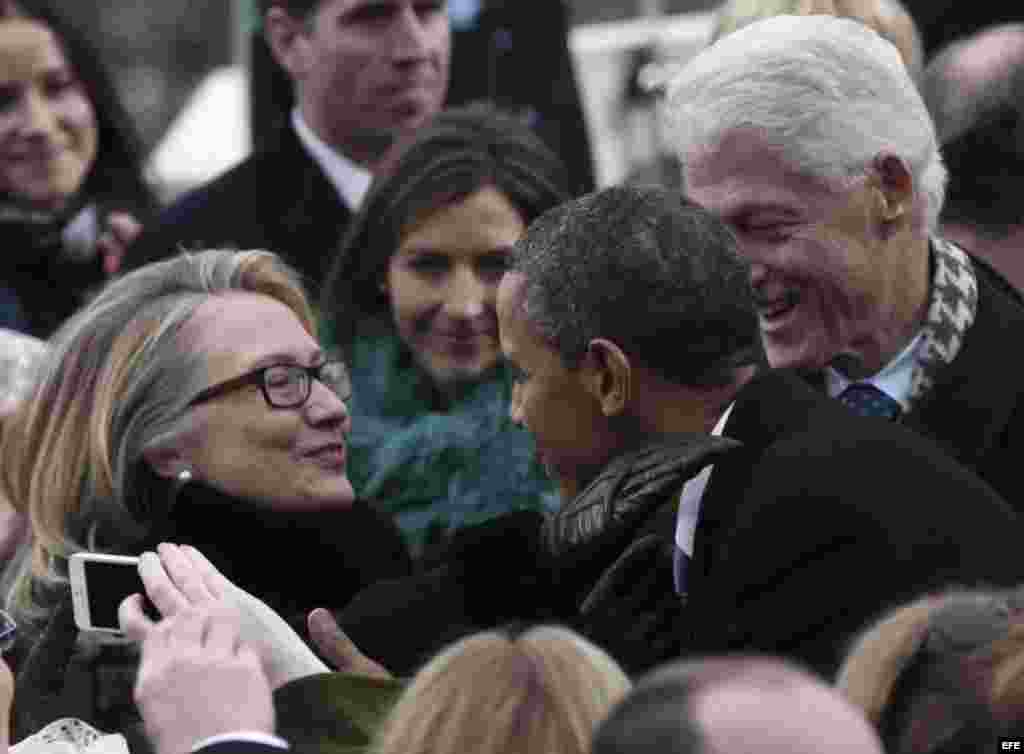 El presidente estadounidense Barack Obama (c) saluda a la Secretaria de Estado, Hillary Clinton (i), en presencia de su esposo, el expresidente Bill Clinton (d), a su llegada a la fachada Oeste del Capitolio antes de su discurso inaugural en Washington,