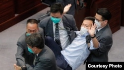 Los guardias de seguridad arrastran al legislador pro democracia Ray Chan durante una reunión legislativa el 8 de mayo en Hong Kong.