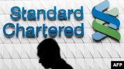 Un hombre pasa frente a las oficinas del Standard Chartered Bank en Hong Kong.