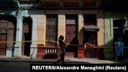 Una mujer pasa frente a varias casas en cuarentena por COVID-19 en un barrio de La Habana. REUTERS/Alexandre Meneghini