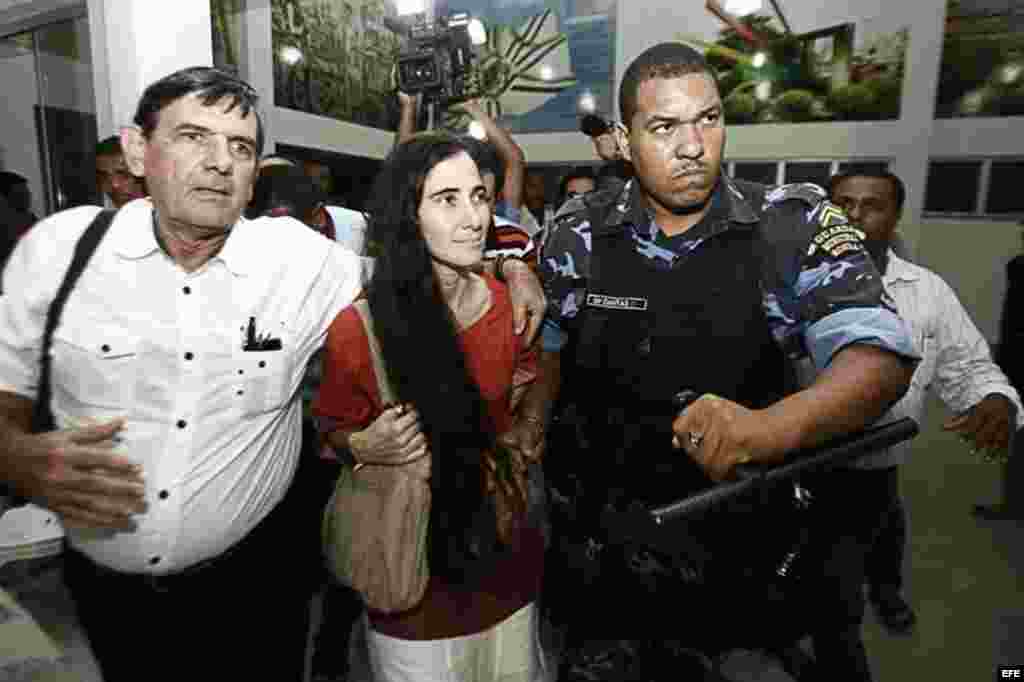 La cubana Yoani Sánchez (c), autora del blog "Generación Y", camina escoltada durante su primera jornada de visita a Brasil hoy, lunes 18 de febrero de 2013, en Feira de Santana.